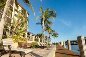 马可岛Holiday Inn Club Vacations Sunset Cove Resort, an IHG Hotel的大楼旁的木板路,有长椅和棕榈树