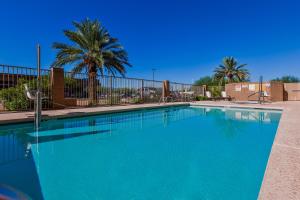 土桑坎德尔伍德套房图森酒店的一座种植了棕榈树和围栏的大型蓝色游泳池