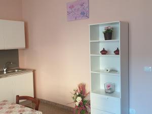 圣泰雷萨迪里瓦Caccia Apartment的白色书架上放着鲜花和花瓶