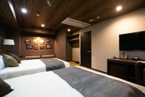 松本The Celecton Matsumoto的酒店客房设有两张床和一台平面电视。
