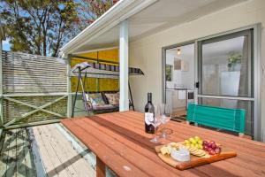 芒阿法埃The Taranui Cottage - Mangawhai Heads Holiday Home的天井上配有带酒杯和水果的木桌