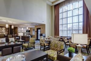 马里兰高地圣路易斯 - 西港驻桥套房假日酒店的酒店大堂设有桌椅和大窗户。