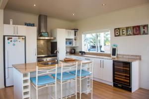 MatarangiWaterfront Wonder - Matarangi Holiday Home的厨房配有白色橱柜和带凳子的台面