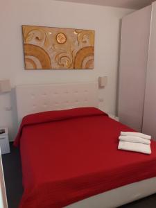 里米尼葛里别墅旅馆的卧室配有红色的床,墙上挂有绘画作品