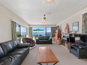 陶波Lofty Lakeviews - Acacia Bay Holiday Home的客厅配有真皮沙发和桌子