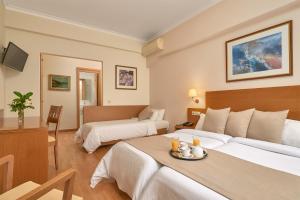 雅典阿托斯酒店的酒店客房设有两张床和一张桌子。