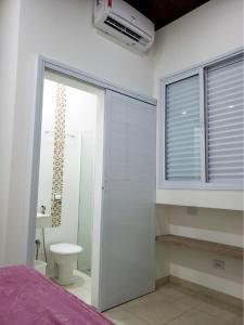普鲁登特总统城Pousada Della Nonna的一间卧室,带卫生间的浴室和窗户