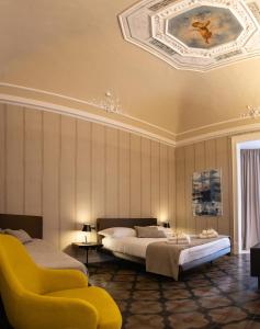 卡塔尼亚B&B Palazzo Perrotta的一间卧室配有两张床和一张黄色椅子