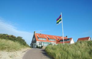 FormerumStrandhotel Terschelling B&B的山上带旗帜的海滩房屋