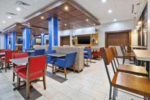 PainesvilleHoliday Inn Express & Suites - Painesville - Concord, an IHG Hotel的一间带桌椅和电视的餐厅