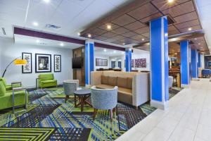 PainesvilleHoliday Inn Express & Suites - Painesville - Concord, an IHG Hotel的大堂设有蓝色的圆柱和桌椅