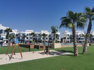 瓜尔达马尔·德尔·塞古拉Oasis Beach juan的公园内拥有棕榈树和公寓的游乐场
