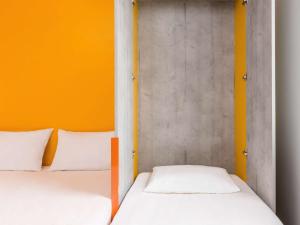 Isneauville宜必思快捷鲁昂北伊诺城酒店的橙色墙壁的客房内的两张床