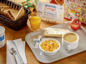马尔芒德Ibis Budget Marmande的早餐盘,包括一碗谷物和一杯咖啡