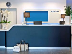 贝尔福贝尔福中心宜必思快捷酒店的办公室里的一个前台,有蓝色的墙壁