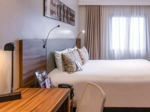 库里提巴美居库里提巴巴特尔酒店的酒店客房设有一张大床和一张书桌。