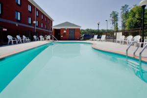 萨福克萨福克智选假日套房酒店的一座带白色椅子的大型游泳池和一座建筑