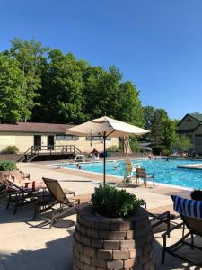 东斯特劳兹堡Pocono Villas Resort的一个带椅子和遮阳伞的游泳池以及游泳池