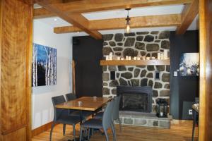 瓦尔达维德Restaurant et Gite Les Passionnés的一间设有石制壁炉、木桌和椅子的用餐室