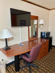 VernonGreen bird Inn的一张桌子,配有电视和椅子,位于酒店的房间