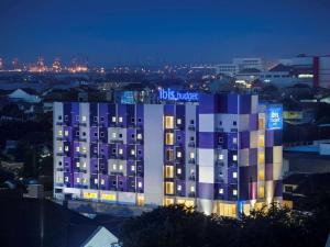 三宝垄Ibis Budget Semarang Tendean - CHSE Certified的一座晚上拥有蓝色和白色外墙的建筑