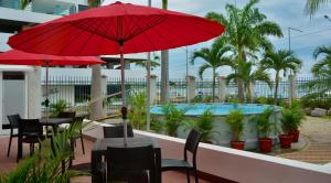 萨利纳斯Hotel Casablanca CHIPIPE的一个带桌子和红色遮阳伞的庭院和一个游泳池