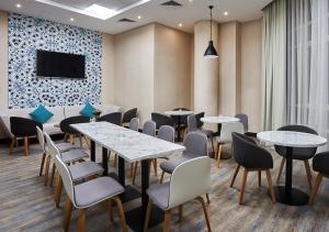 沙迦TIME Express Hotel Al Khan的一间带桌椅和电视的用餐室