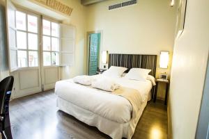 塞维利亚圣克鲁斯之家精品酒店的一间卧室配有一张带白色床单的大床