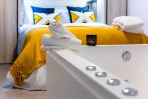 埃尔瓦Apartamentos Hervás Suites的一间卧室设有一张黄色的床和一个白色浴缸