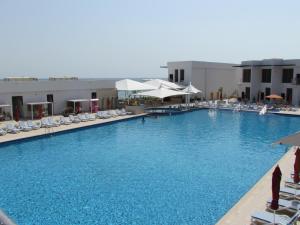 迪巴Mirage Bab Al Bahr Beach Resort的一个带椅子和遮阳伞的大型游泳池