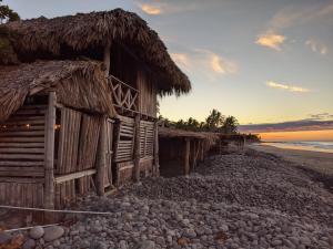 拉利伯塔德Pelicano Surf Camp的日落时分海滩上的旧棚屋