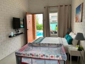 龙运加拉海角之家旅馆的一间卧室设有一张床、一台电视和一个游泳池