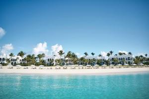 West End VillageCap Juluca, A Belmond Hotel, Anguilla的海滩上摆放着白色的遮阳伞和椅子