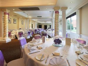 温彻斯特温彻斯特韦塞克斯美居酒店的宴会厅配有白色桌子和紫色椅子