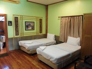 Ban Khok Mai Den (1)Nang Phraya Resort的配有绿色墙壁和木地板的客房内的两张床