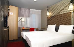 第比利斯ibis Tbilisi Stadium的酒店客房设有一张大床和一张红色椅子。