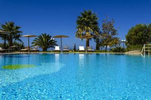 马斯蒂查里小村酒店的一个带椅子和遮阳伞的大型蓝色游泳池