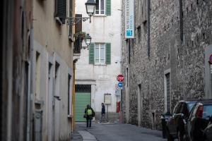 布雷西亚LUOGO COMUNE Ostello的两个人在小巷里走下一条街道