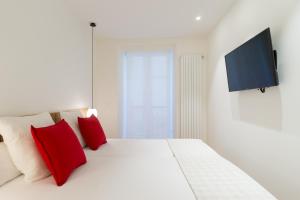 圣塞瓦斯蒂安Fermin Suite - Iberorent Apartments的配有红色枕头的白色床和平面电视
