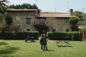莫格罗拉霍尤卡德尔帕斯酒店的站在房子前面的男人和女人