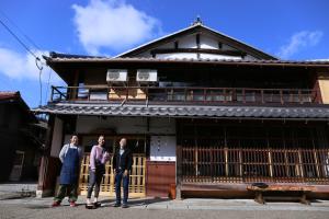 NagaokaGuesthouse Izame Ann的三人站在一座建筑前面