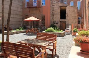 Del Norte温莎酒店及餐厅的庭院设有2张长椅、桌子和遮阳伞