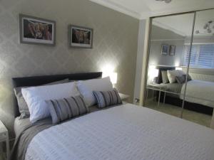 巴洛赫Levenview Holiday Apartment Loch Lom的卧室配有一张带镜子的白色大床