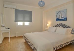 科孚镇The Bluehouse - Spacious top floor flat with parking, by Mon Repos beach的一间卧室配有一张床、一张桌子和一个窗户。