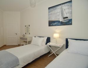 科孚镇The Bluehouse - Spacious top floor flat with parking, by Mon Repos beach的一间卧室设有两张床和一张墙上的桌子。