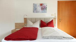 HöfenFerienwohnung Dreer的一间卧室配有红色和白色枕头的床