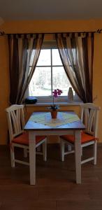 KolonieFerienwohnung Wasserlilie的餐桌、两把椅子和窗户
