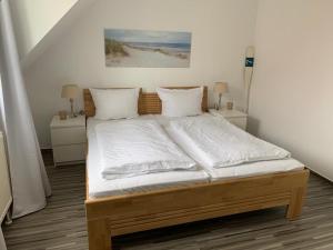 奥斯赛拜-屈隆斯博恩Appartementhaus Ulmenhof的卧室配有一张带白色床单和枕头的大床。