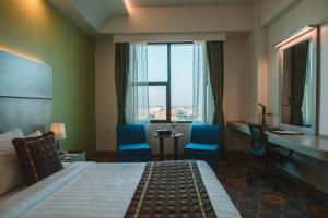 曼德勒Ritz Grand Hotel Mandalay的配有一张床、一张书桌和一扇窗户的酒店客房