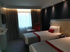 明斯特Holiday Inn Express Ramsgate – Minster, an IHG Hotel的酒店客房,设有两张床和一张红色椅子